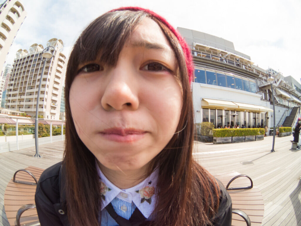 ちょっとしかめっ面の女性のアップショットを魚眼レンズで撮影。
