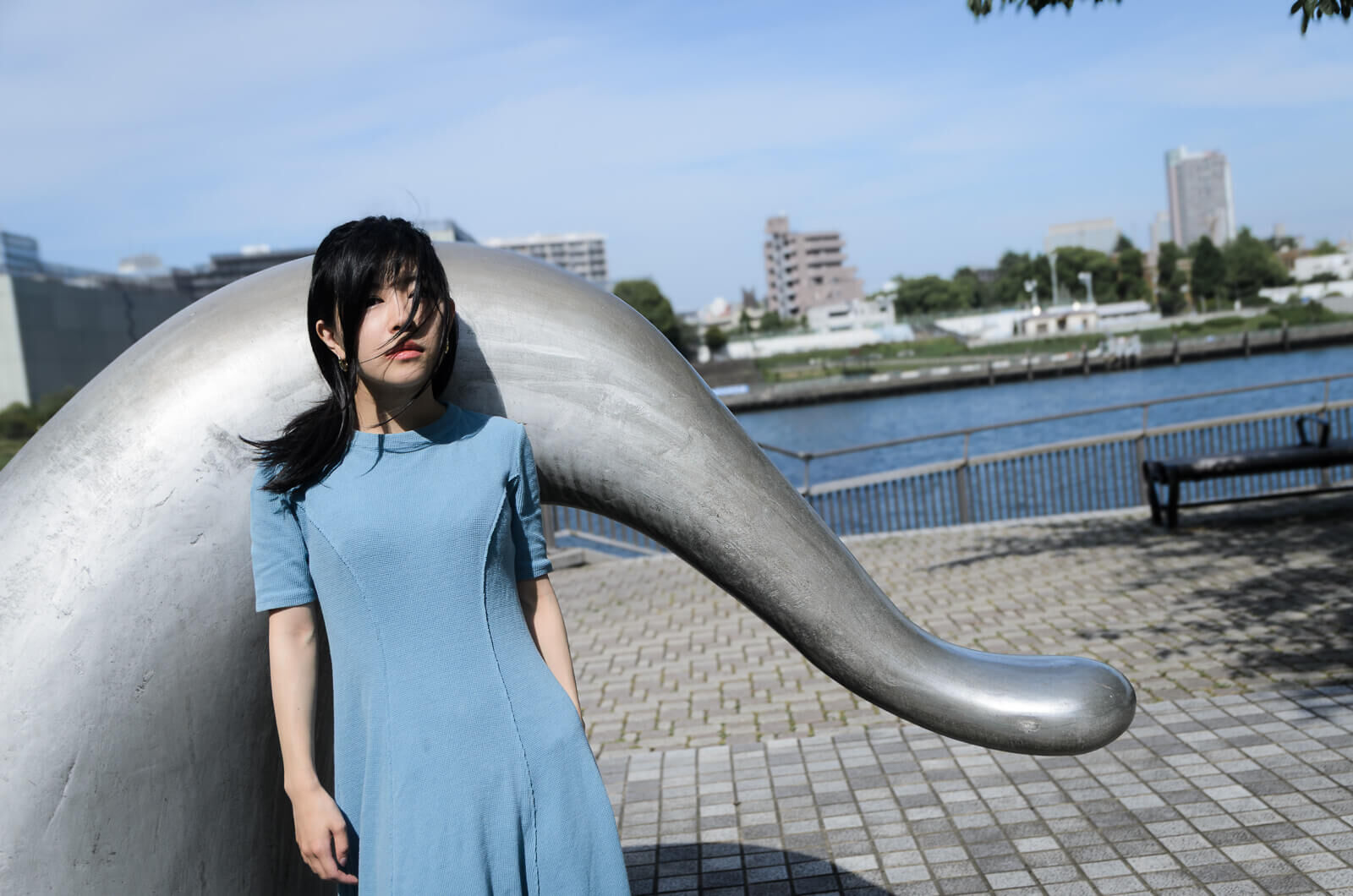 謎のオブジェを背に立つ女性